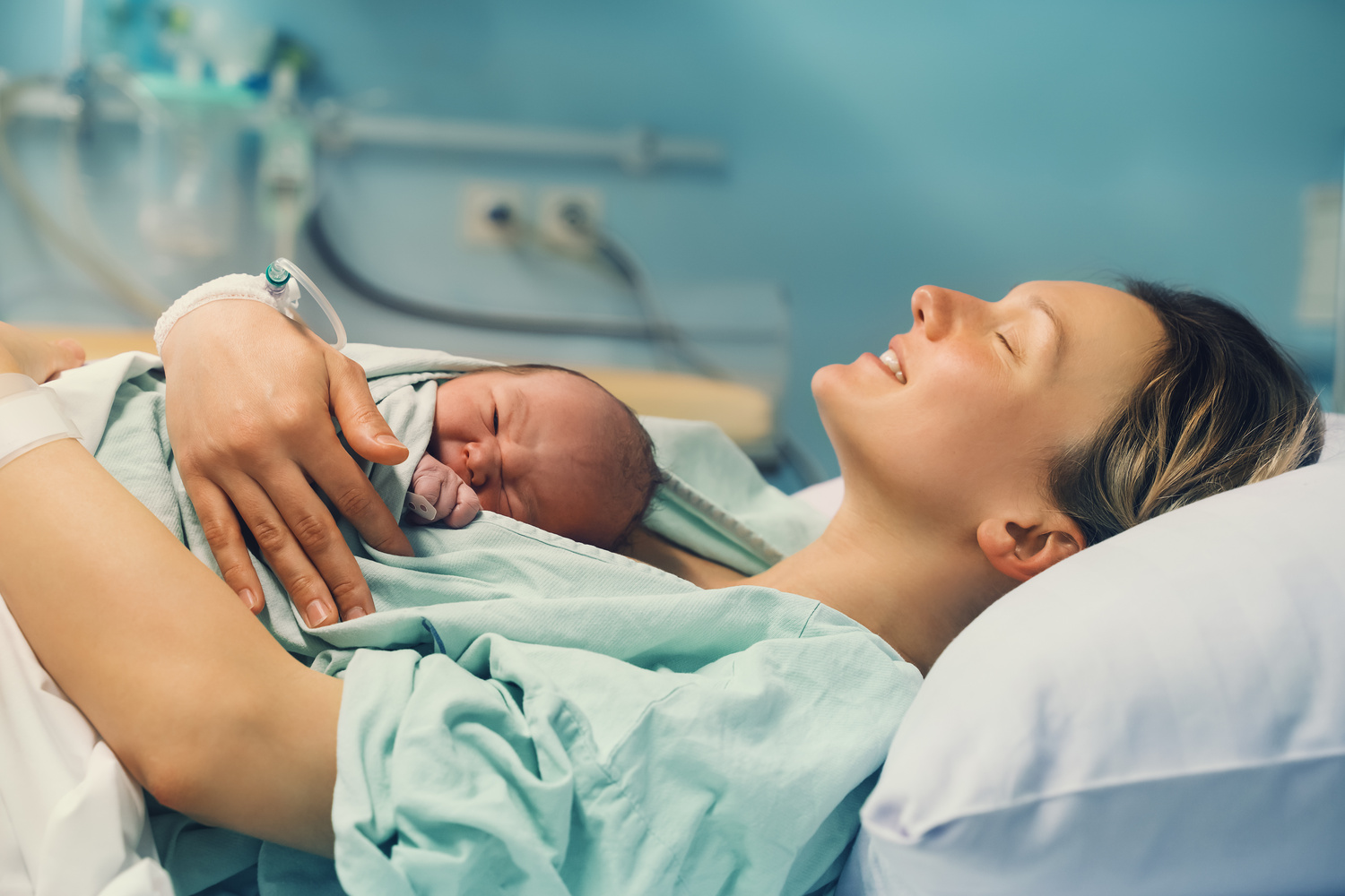 Mother and newborn. Child birth in maternity hospital. Young mom hugging her newborn baby after delivery. Woman giving birth.